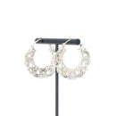 A pair of silver  hoop earrings with decorative scroll work accents.