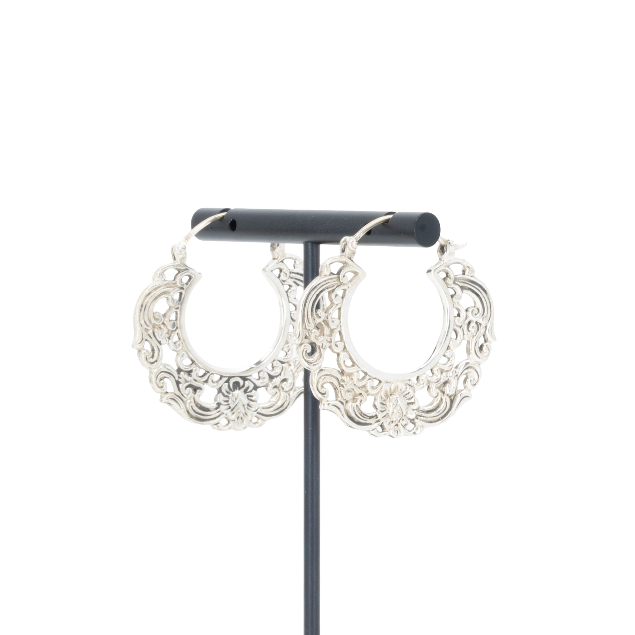 A pair of silver  hoop earrings with decorative scroll work accents.