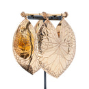 A pair of large leaf-shaped rose gold weights with intricate engraved vein patterns.