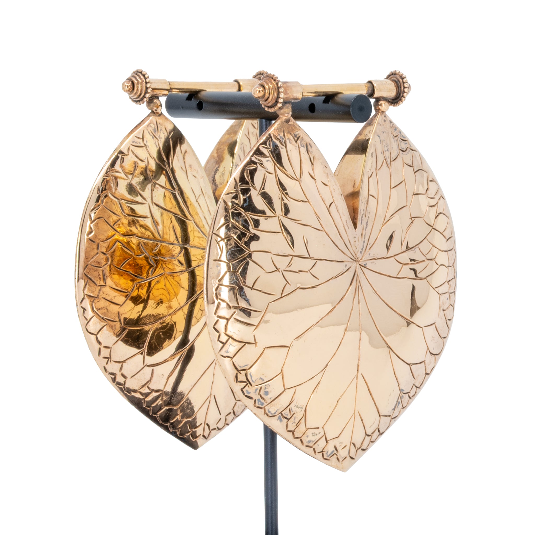 A pair of large leaf-shaped rose gold weights with intricate engraved vein patterns.
