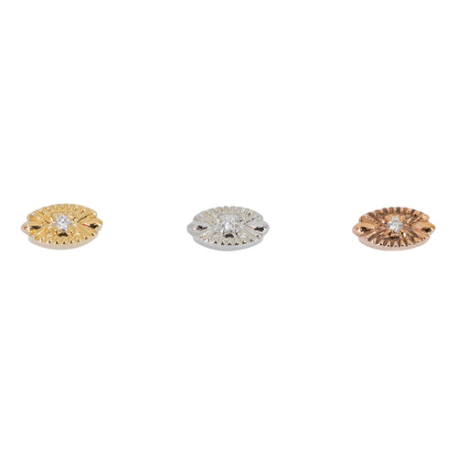 Three round diamond stud push pin earrings in a prong setting on a gold oval with laser etched accents pointing toward the center.  One yellow gold, one white gold, and one rose gold.