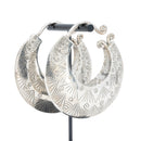 Large silver crescent weights with intricate geometric and sunburst engraved patterns.