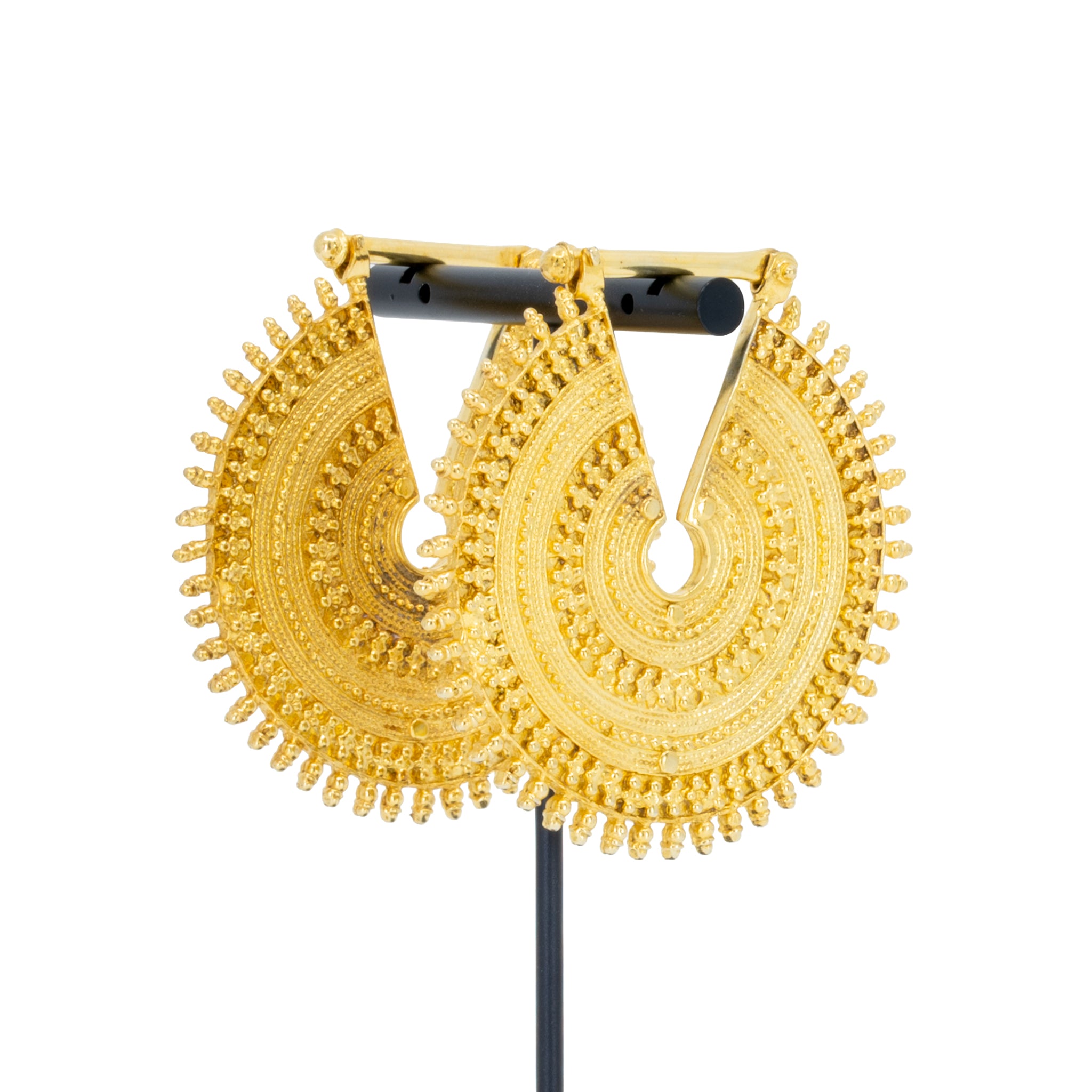 A pair of ornate yellow gold weights with intricate concentric beadwork.