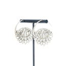 A pair of silver  hoop earrings with a lotus at the bottom.