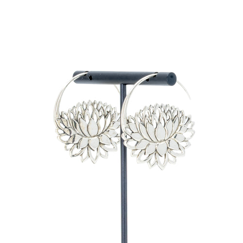 A pair of silver  hoop earrings with a lotus at the bottom.