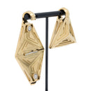 A pair of yellow gold plated weights in a tetrahedron shape with triangles indentations on each side. One weight is open showing its magnetic closure.
