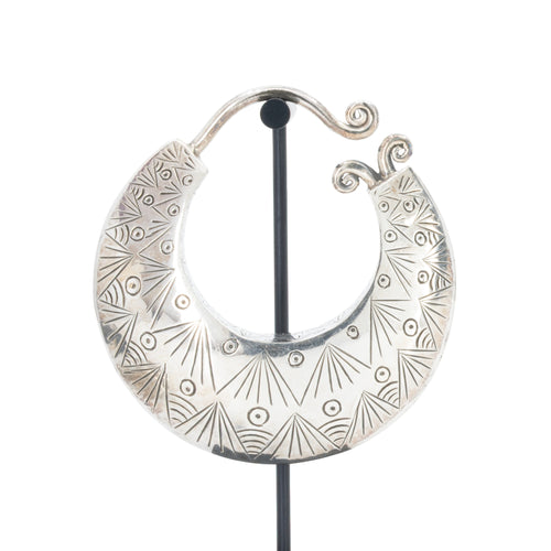 Large silver crescent weight with intricate geometric and sunburst engraved patterns.